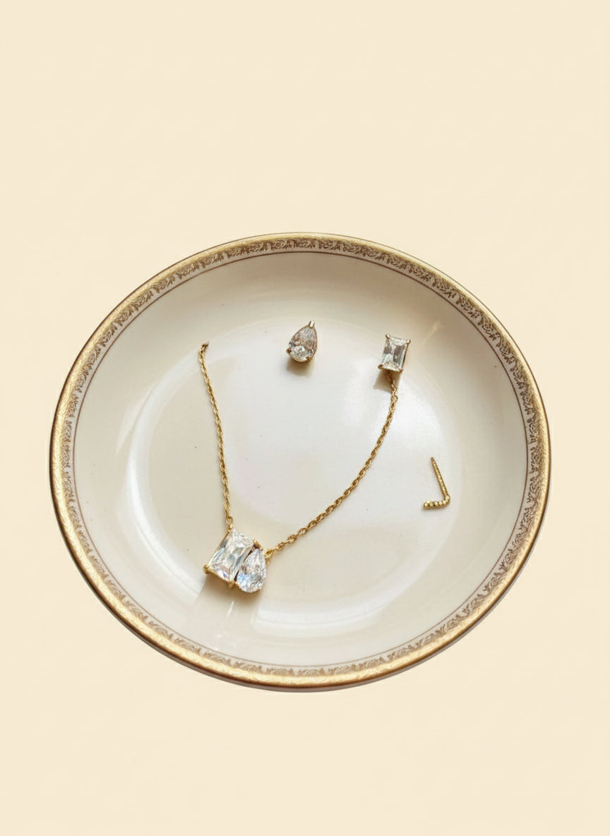 Jewelry set including necklace and earrings on a decorative plate with a beige background